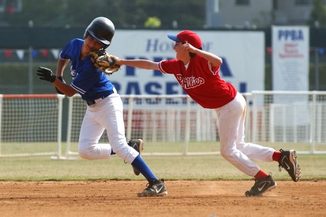 Spencer Swai of the Dodgers is tagged out by Phillies shortstop Kyle Warner during a rundown in the sixth inning of Saturday's Bronco playoff game at the Palisades Recreation Center.